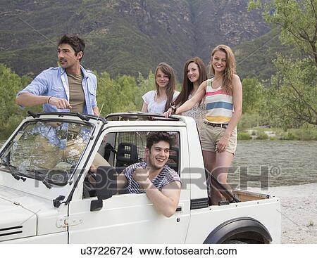 Friends standing on back of off road vehicle View Large Photo Image Picture - Friends standing on back of off road vehicle. Fotosearch