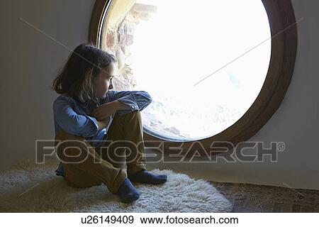 Girl sitting on floor gazing through circular window View Large Photo Image Stock Photo - Girl sitting on floor gazing through circular window. Fotosearch