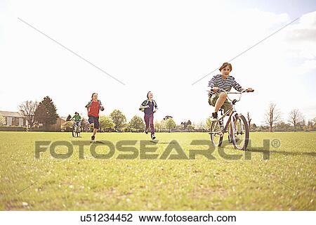 Group of boys running and cycling on playing field View Large Photo Image Stock Image - Group of boys running and cycling on playing field. Fotosearch