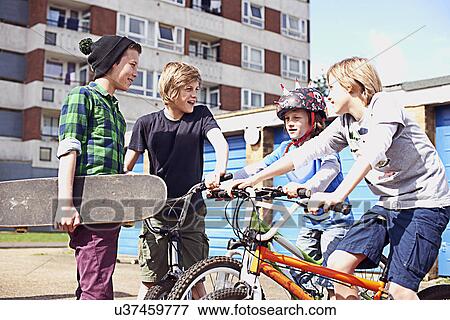 Stock Photo - Group of boys talking with bikes and skateboard. Fotosearch