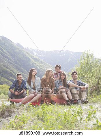 Stock Photo - Group of six young adult friends sitting on canoe, Piemonte, Italy. Fotosearch