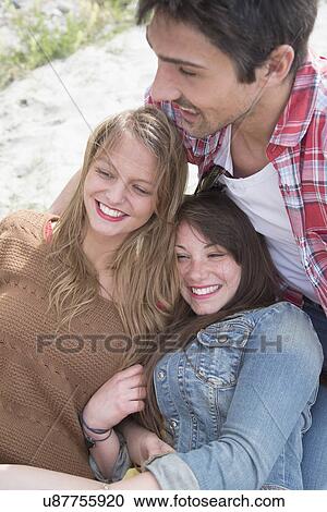 Stock Image - Group of three young adult friends having a laugh. Fotosearch
