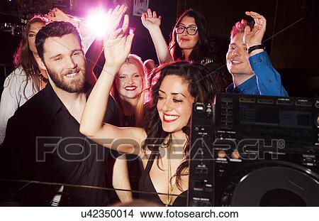 Picture - Group of young men and women dancing in nightclub. Fotosearch