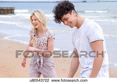 Stock Image - Happy young couple strolling on beach. Fotosearch