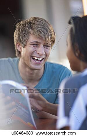 Laughing young couple looking at book View Large Photo Image Stock Image - Laughing young couple looking at book. Fotosearch