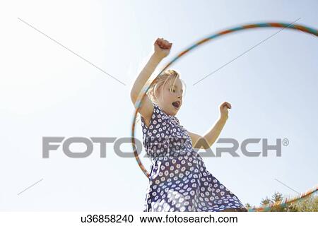 Stock Image - Low angle view of girl playing with plastic hoop. Fotosearch