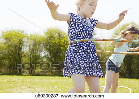 Stock Photo - Low angle view of two girls playing with plastic hoops. Fotosearch