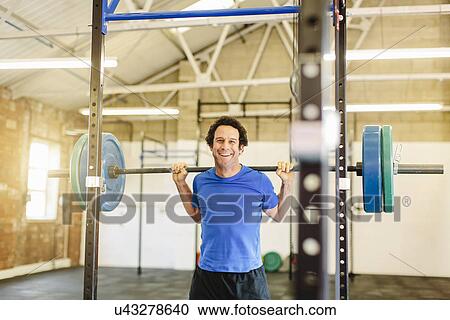 Man lifting barbell in gym View Large Photo Image Stock Image - Man lifting barbell in gym. Fotosearch