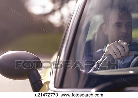 Stock Image - Man sitting behind wheel of car. Fotosearch