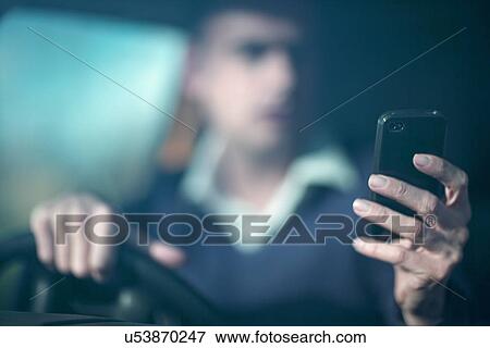 Stock Photo - Man using smartphone whilst driving. Fotosearch