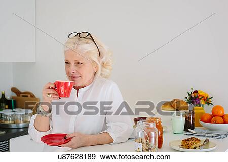 Mature woman at home having a coffee View Large Photo Image Stock Photo - Mature woman at home having a coffee. Fotosearch