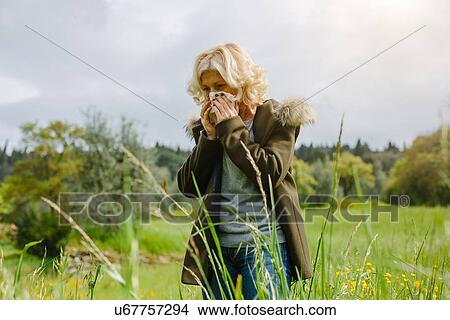 Mature woman blowing her nose whilst out in fields View Large Photo Image Picture - Mature woman blowing her nose whilst out in fields. Fotosearch