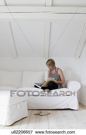 Mature woman sitting cross legged on sofa reading book View Large Photo Image Stock Photo - Mature woman sitting cross legged on sofa reading book. Fotosearch