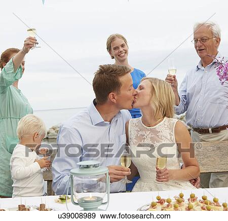 Mid adult couple kissing and making a toast with group of friends View Large Photo Image Stock Photo - Mid adult couple kissing and making a toast with group of friends. Fotosearch