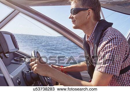 Mid adult male driving boat View Large Photo Image Stock Image - Mid adult male driving boat. Fotosearch