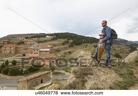 Stock Photo - Mid adult man and daughter gazing at rural view. Fotosearch