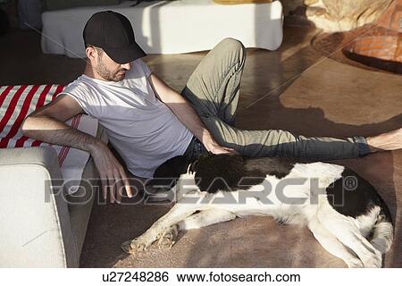 Mid adult man petting lazy dog on patio View Large Photo Image Stock Photograph - Mid adult man petting lazy dog on patio. Fotosearch