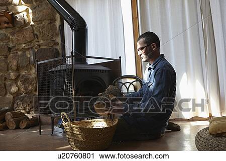 Mid adult man preparing log fire View Large Photo Image Stock Image - Mid adult man preparing log fire. Fotosearch