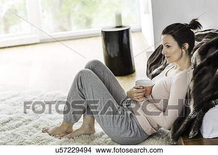 Mid adult woman sitting on floor with coffee View Large Photo Image Picture - Mid adult woman sitting on floor with coffee. Fotosearch