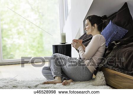 Mid adult woman sitting on floor with coffee View Large Photo Image Stock Photo - Mid adult woman sitting on floor with coffee. Fotosearch