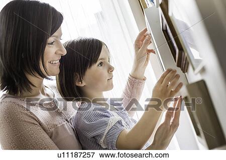 Mother and daughter adjusting picture View Large Photo Image Stock Photo - Mother and daughter adjusting picture. Fotosearch