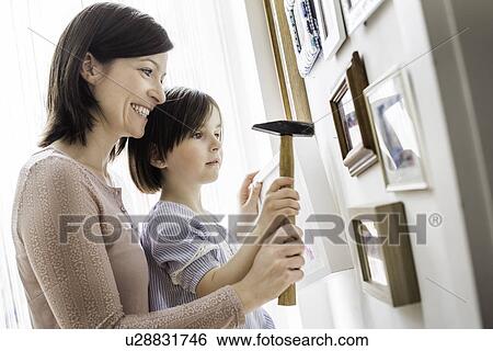 Mother and daughter hanging picture on wall View Large Photo Image Stock Photograph - Mother and daughter hanging picture on wall. Fotosearch