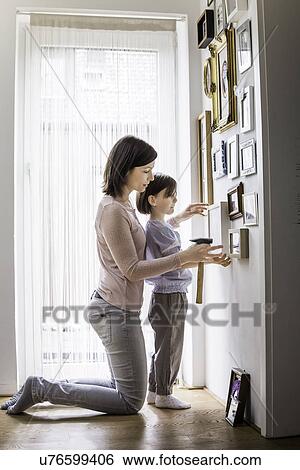 Mother and daughter hanging picture on wall View Large Photo Image Stock Photograph - Mother and daughter hanging picture on wall. Fotosearch