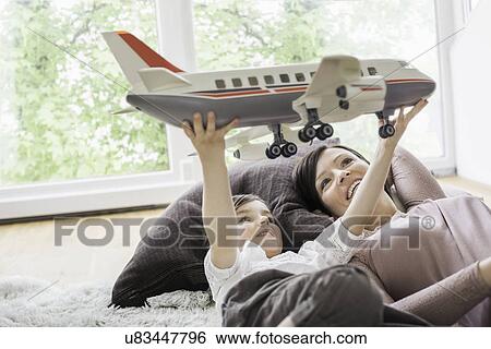 Stock Photograph - Mother and daughter playing with toy aeroplane. Fotosearch