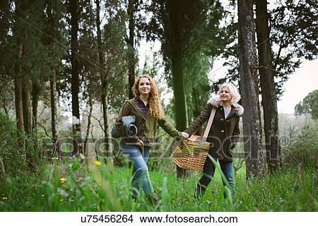 Picture - Mother and teenage daughter carrying picnic basket. Fotosearch
