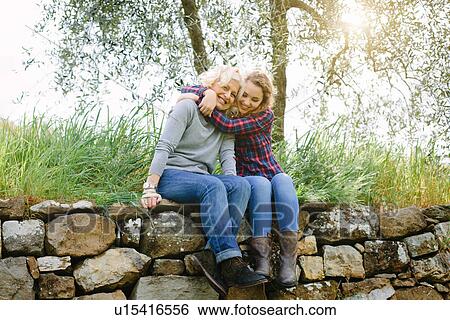 Mother and teenage daughter hugging on dry stone wall View Large Photo Image Stock Photograph - Mother and teenage daughter hugging on dry stone wall. Fotosearch