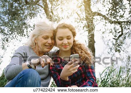 Picture - Mother and teenage daughter looking at smartphone. Fotosearch