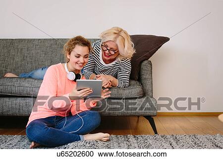 Mother and teenage daughter looking at digital tablet at home View Large Photo Image Stock Image - Mother and teenage daughter looking at digital tablet at home. Fotosearch
