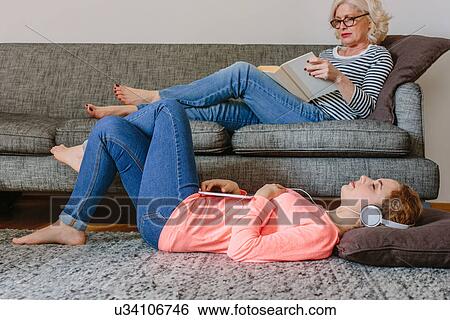 Stock Photograph - Mother and teenage daughter relaxing in sitting room at home. Fotosearch
