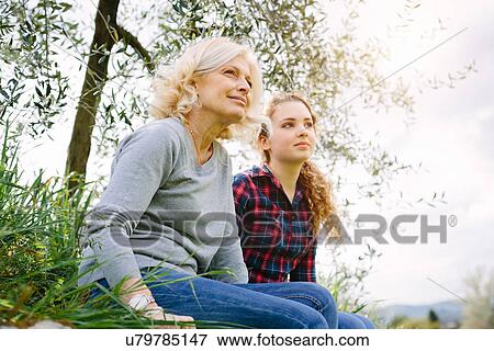 Mother and teenage daughter sitting on grass View Large Photo Image Stock Photo - Mother and teenage daughter sitting on grass. Fotosearch