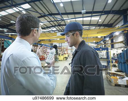 Stock Photo - Office and factory worker checking sound volume in factory. Fotosearch