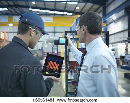 Stock Image - Office and factory worker using digital tablet and infra red camera to check power use in factory. Fotosearch