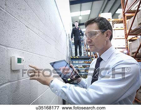Office worker checking thermostat in factory View Large Photo Image Stock Photo - Office worker checking thermostat in factory. Fotosearch