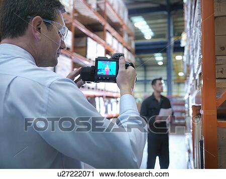 Stock Image - Office worker taking thermal image with camera in factory. Fotosearch