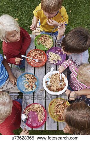 Overhead view of seven children eating spaghetti at picnic table View Large Photo Image Stock Photography - Overhead view of seven children eating spaghetti at picnic table. Fotosearch