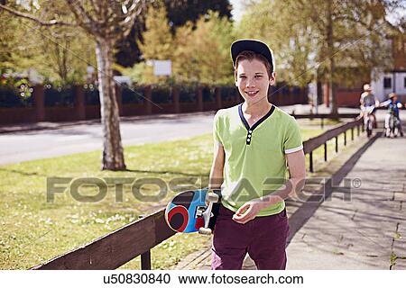 Portrait of boy holding skateboard View Large Photo Image Stock Image - Portrait of boy holding skateboard. Fotosearch