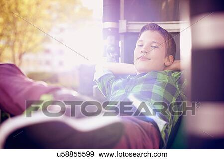 Stock Photo - Portrait of boy relaxing with hands behind head. Fotosearch