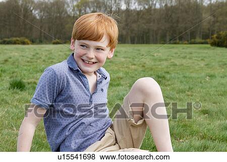 Portrait of boy sitting in field View Large Photo Image Stock Photo - Portrait of boy sitting in field. Fotosearch