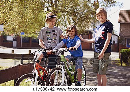 Stock Image - Portrait of boys on pavement with bikes. Fotosearch