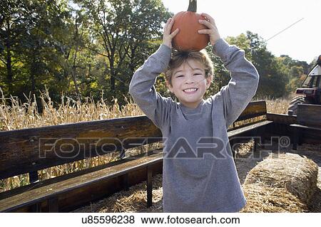 Portrait of cute boy holding up pumpkin View Large Photo Image Stock Photo - Portrait of cute boy holding up pumpkin. Fotosearch