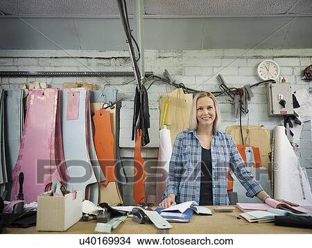 Portrait of fashion designer at cutting desk in clothing factory, smiling View Large Photo Image Picture - Portrait of fashion designer at cutting desk in clothing factory, smiling. Fotosearch