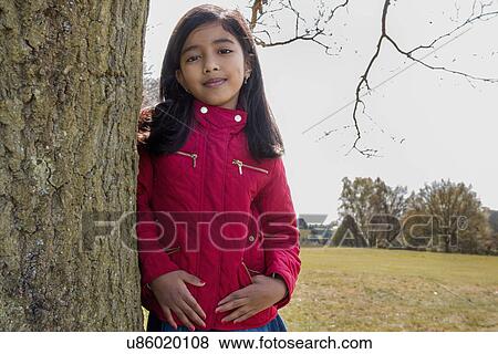 Stock Photo - Portrait of girl leaning against tree trunk. Fotosearch