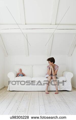 Portrait of mid adult mother and baby daughter gazing at each other on sofa View Large Photo Image Stock Photo - Portrait of mid adult mother and baby daughter gazing at each other on sofa. Fotosearch