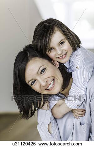Stock Photograph - Portrait of mother and daughter hugging. Fotosearch