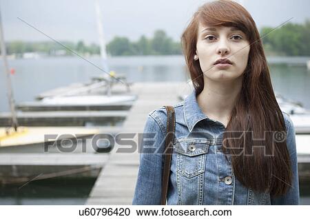 Stock Image - Portrait of serious young woman by lake. Fotosearch