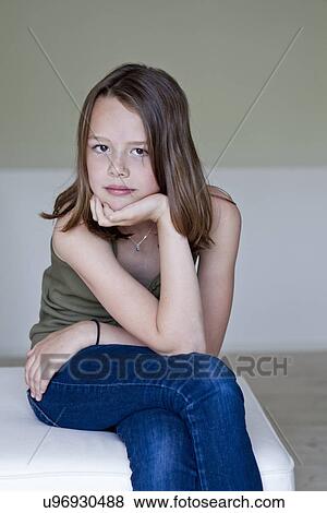 Stock Photo - Portrait of sullen twelve year old girl with hand on chin. Fotosearch